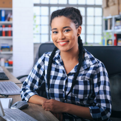 A woman with braids smiling at the camera in an office setting.
